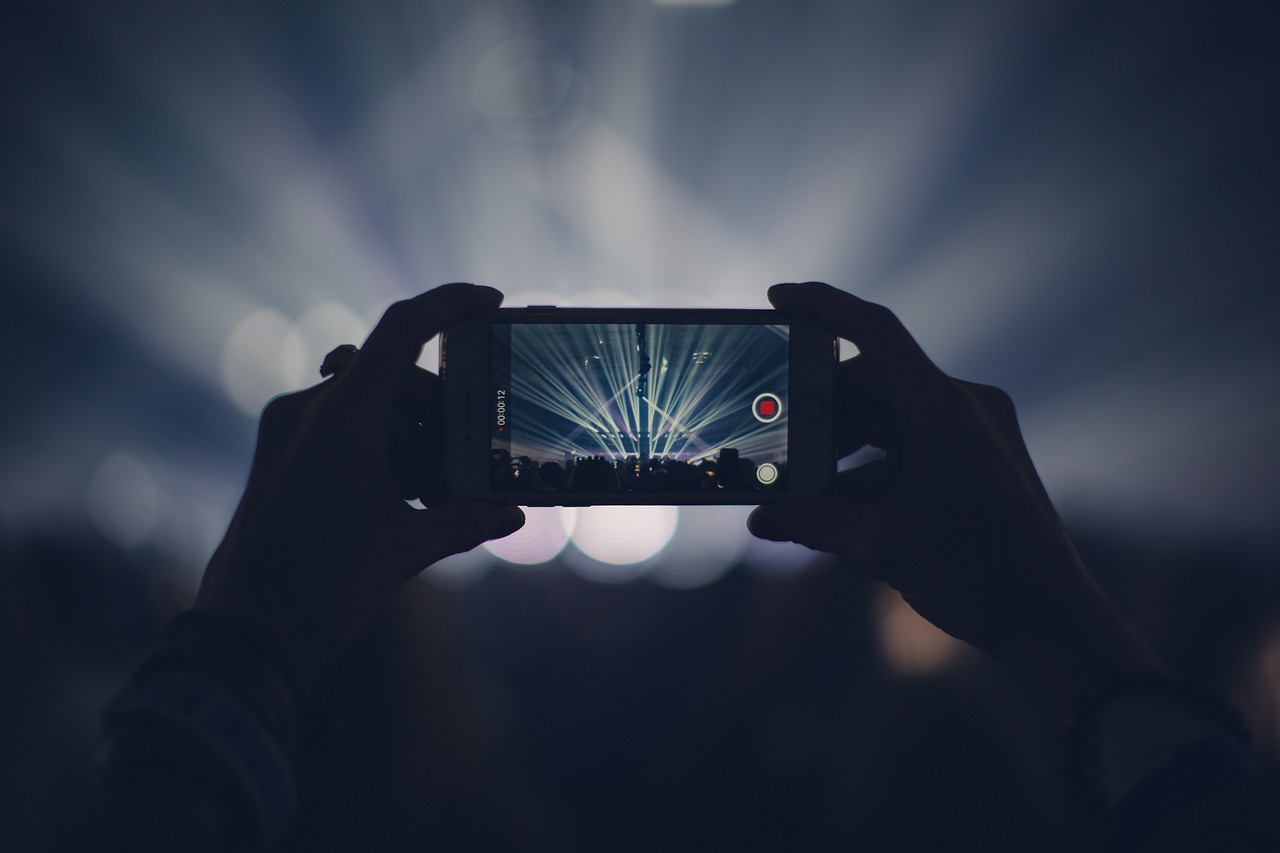 Publikum bei einer Veranstaltung hält Smartphones mit Taschenlampenlicht in die Höhe